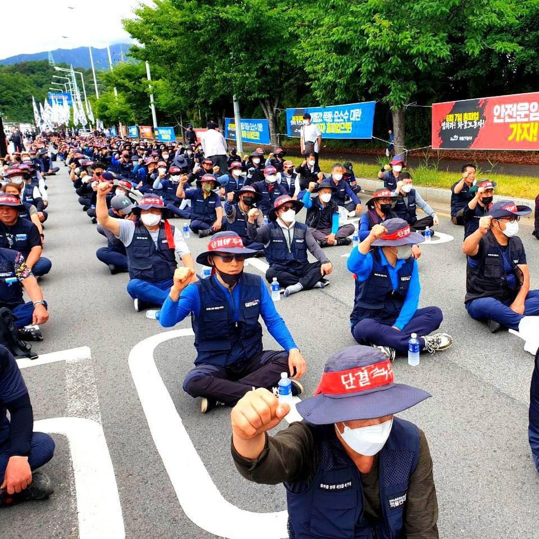 Strejkande lastbilschaufförer i Sydkora sitter på vägen med knutna nävar